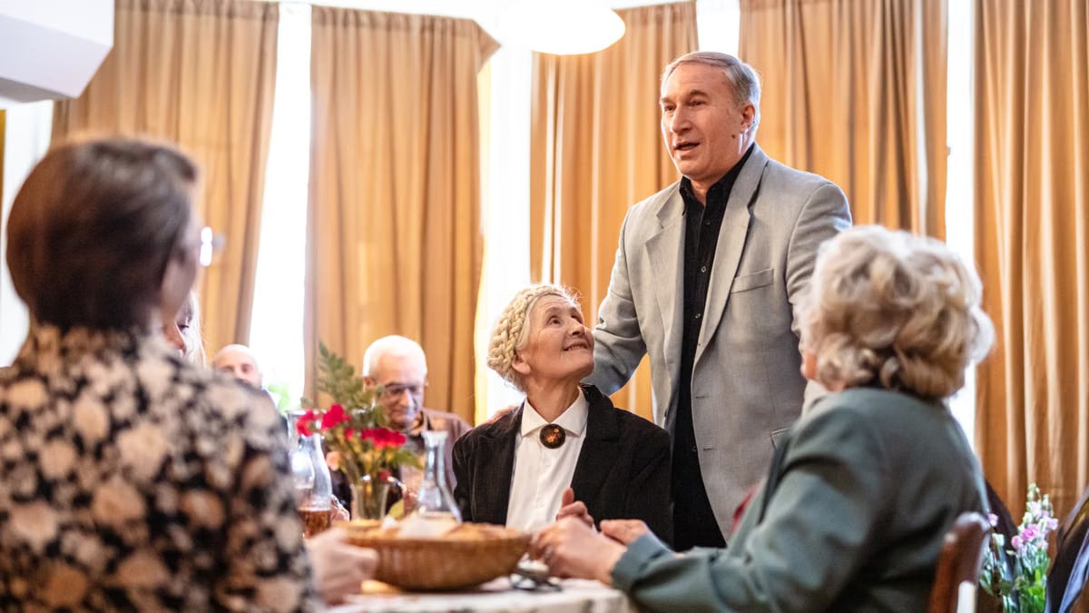 Senior man delivers a heartfelt toast at a cozy family gathering in a restaurant setting.